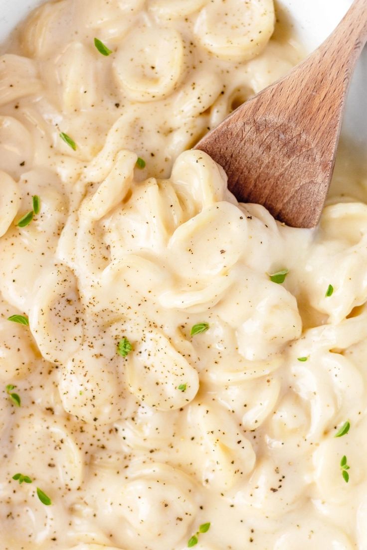 a wooden spoon in a bowl filled with macaroni and cheese