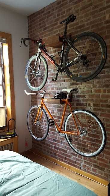 two bikes mounted to the side of a brick wall next to a bed in a bedroom