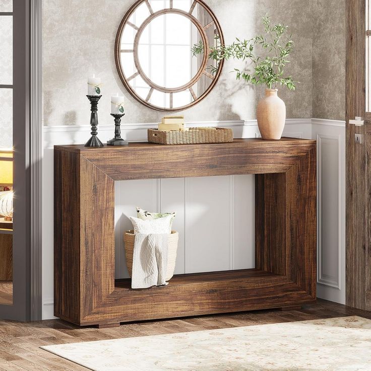 a wooden table with a mirror and vase on it next to a rug in a room