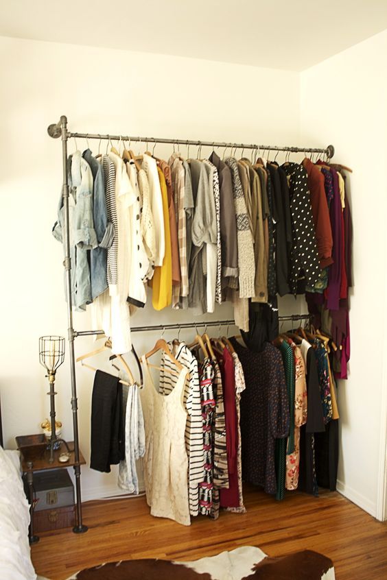 a closet with clothes hanging on the wall and an open rack full of shirts next to it