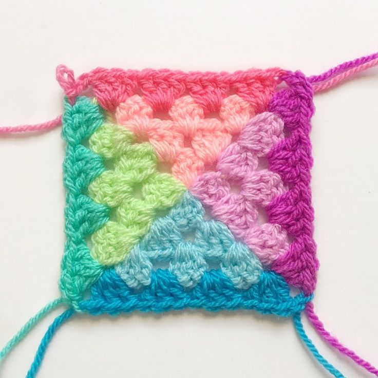 a crocheted square is shown with yarn in the middle and two colors on each side