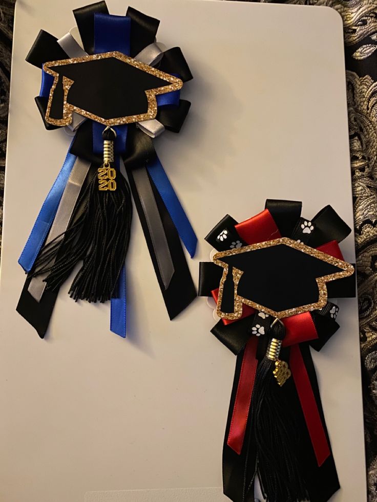 two black and red graduation ribbons on a white board with gold trim, one in the shape of a graduate's cap