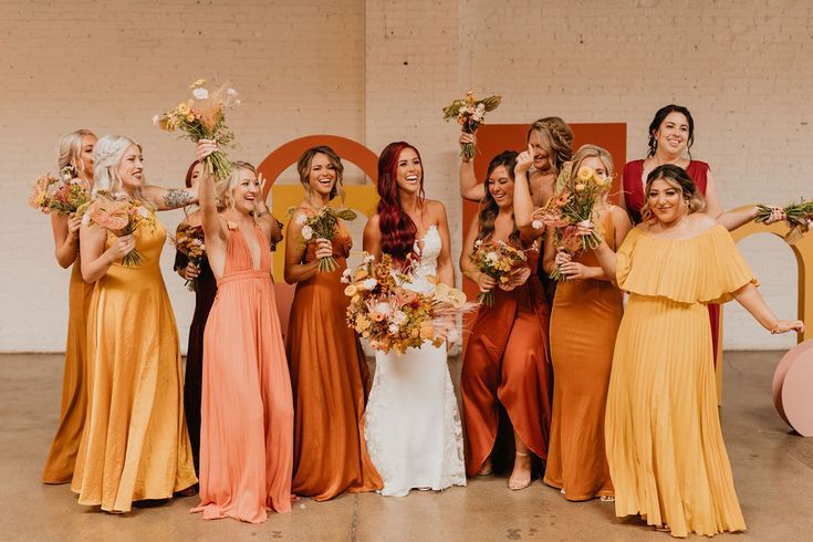 a group of women standing next to each other holding bouquets in their hands and posing for the camera