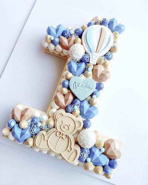 the letter e is made out of fondant and decorated with blue, white and gold decorations