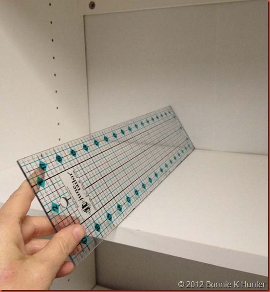 a person holding up a piece of paper with numbers on it in front of a shelf