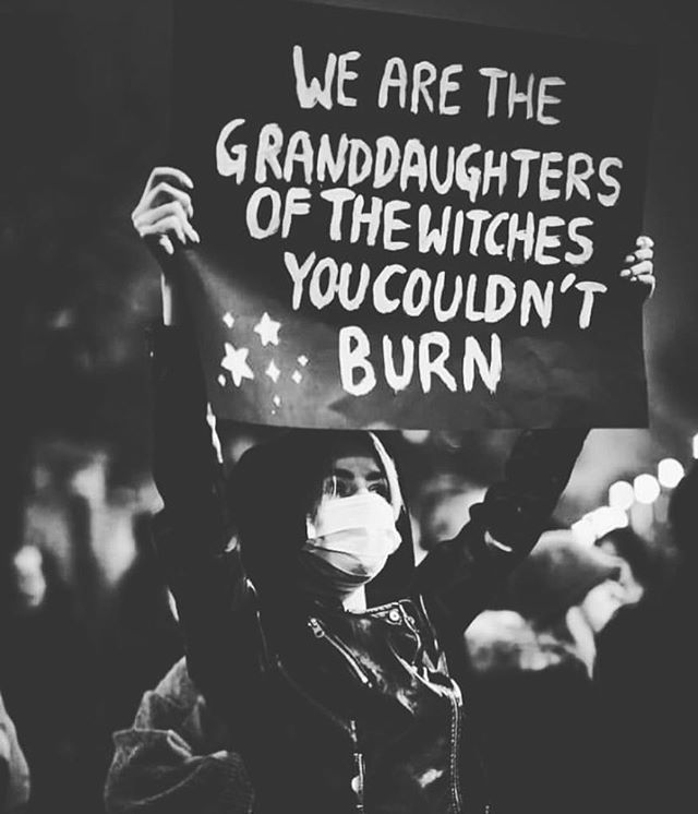 a woman holding up a sign that says we are the granddaughters of the witches you couldn't burn