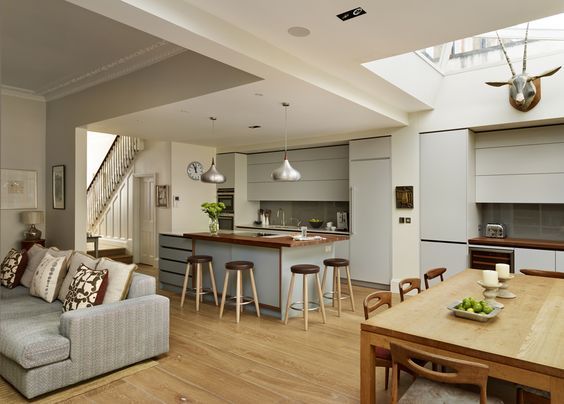 a living room filled with furniture next to a kitchen and dining area on top of a hard wood floor