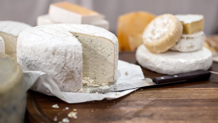 several different types of cheese on a cutting board with a knife and some other food items