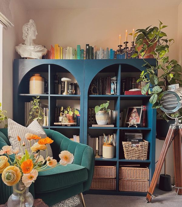 a living room filled with lots of furniture and flowers on top of a book shelf