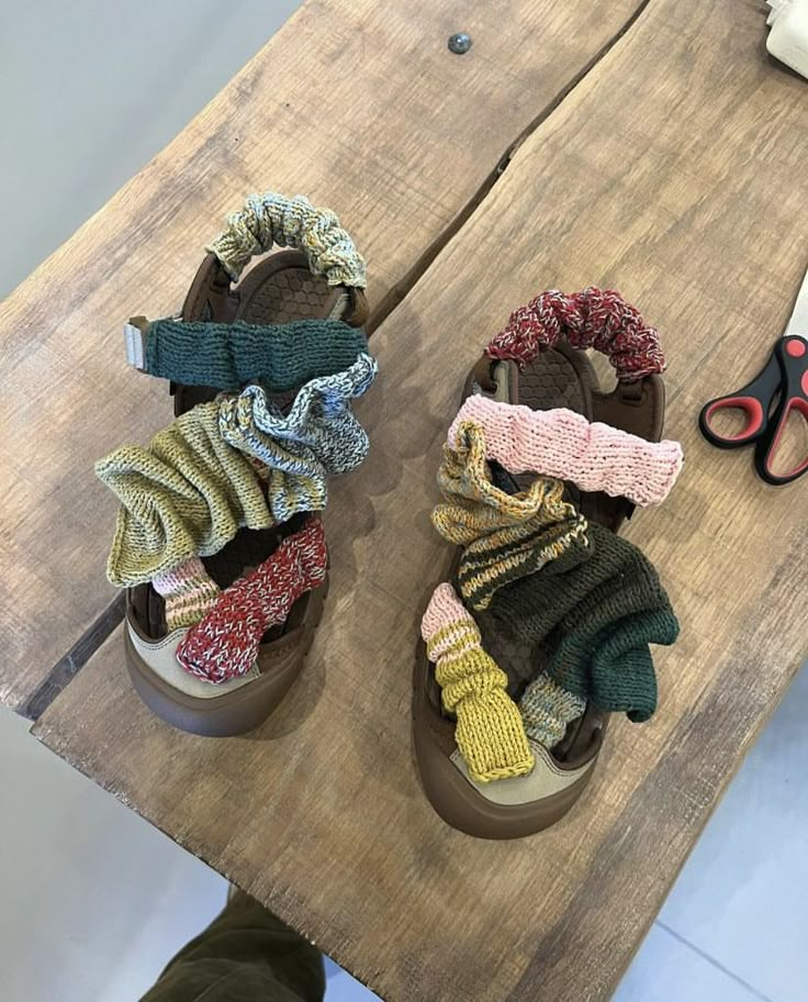 two pairs of sandals are sitting on a wooden table with scissors and other items in the background