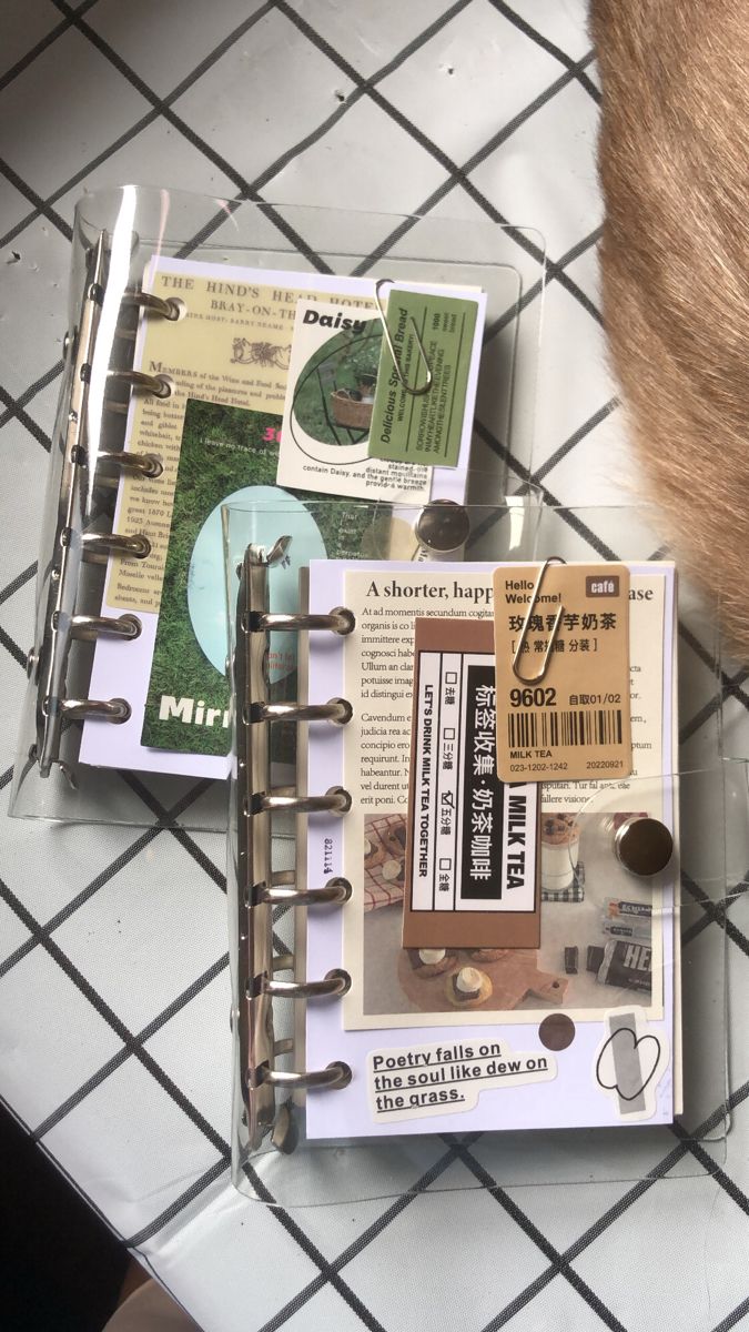 an open planner book sitting on top of a white tiled floor next to a cat