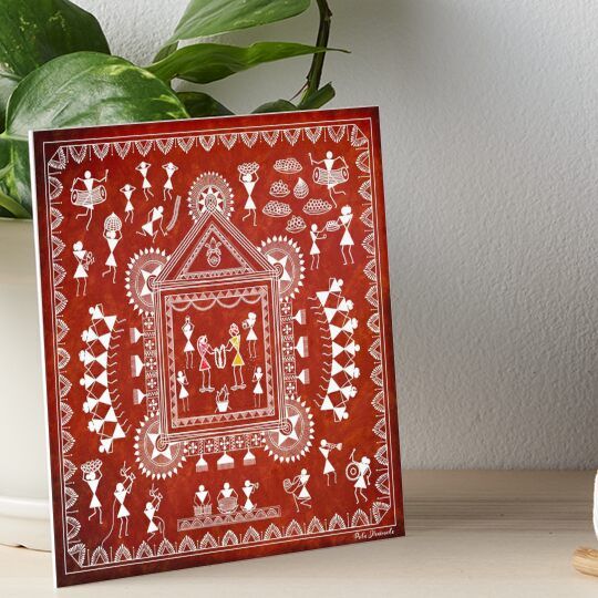 a red and white painting on a table next to a potted plant