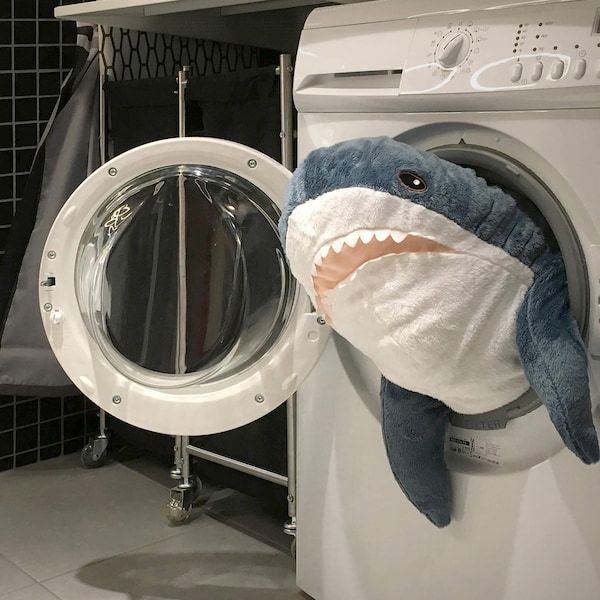 a stuffed shark is in the front of a washing machine with its mouth open and it's head sticking out