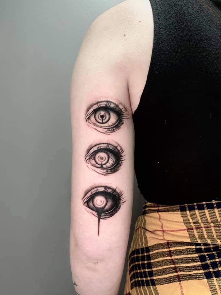 a woman's arm with three eye tattoos on it