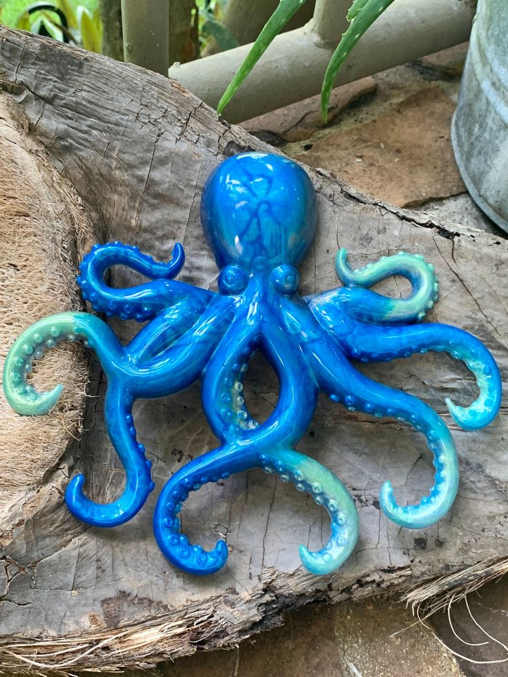 an octopus figurine sitting on top of a piece of wood