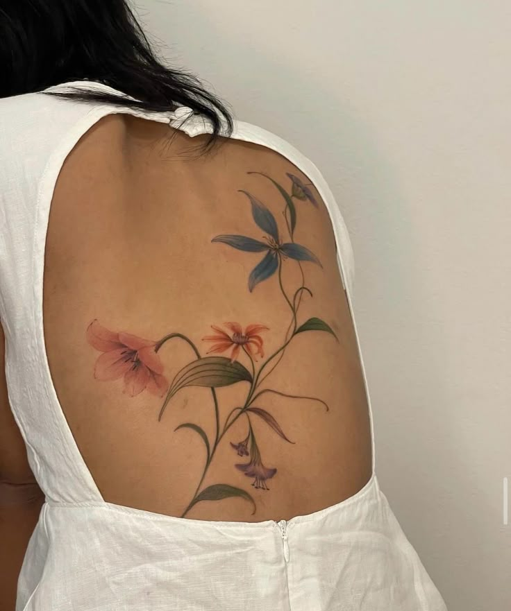 the back of a woman's shoulder with flowers painted on it and leaves in the background