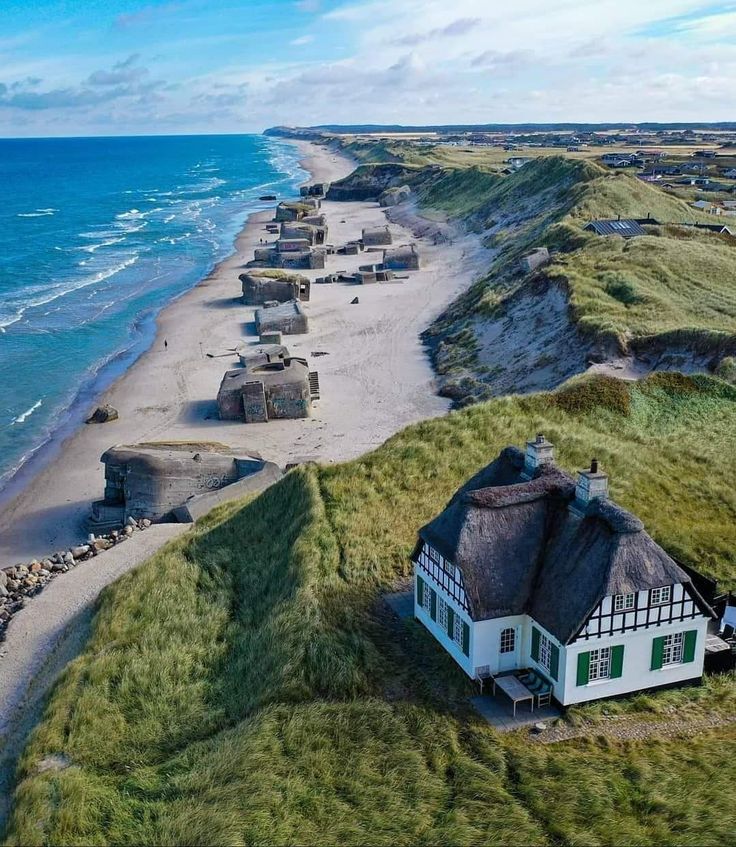 an aerial view of a house on the beach next to the ocean with thatched roofs