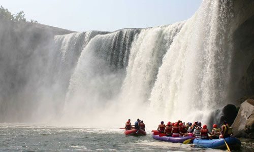 a group of people on rafts in front of a waterfall