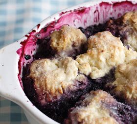 blueberry cobbler in a white dish on a checkered tableclothed cloth