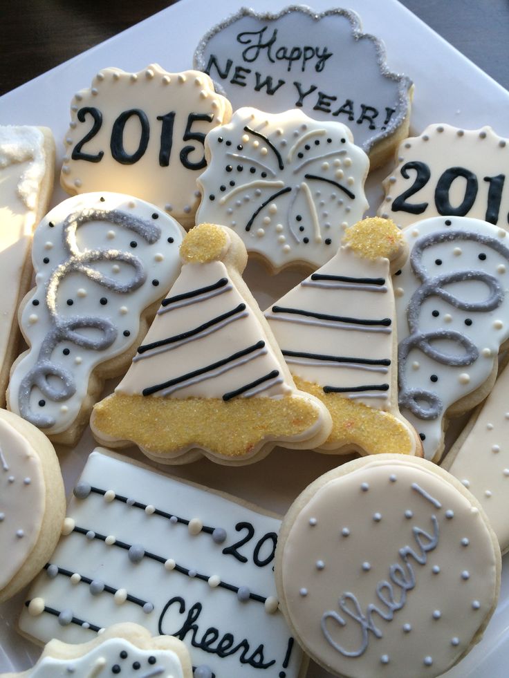 decorated cookies in the shape of christmas trees and new year's eve signs on a platter