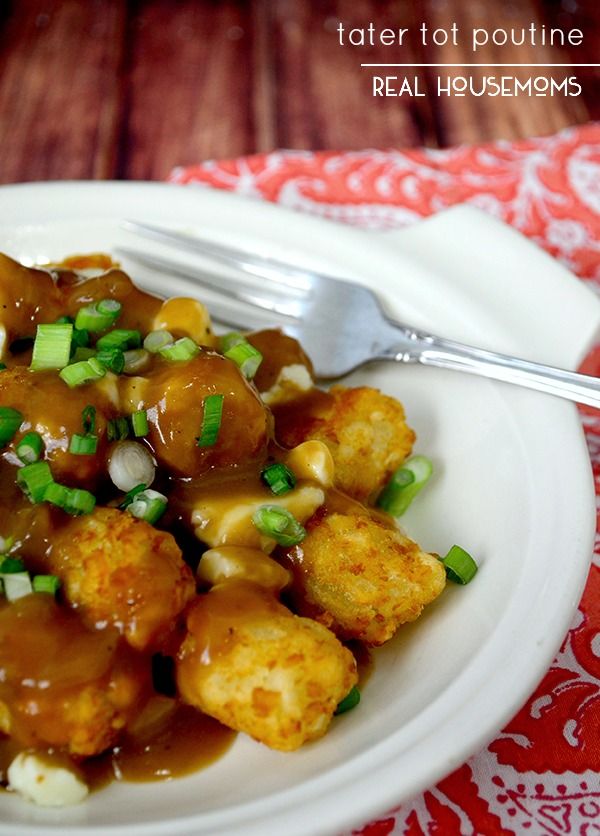 a white plate topped with tater tots covered in gravy and green onions