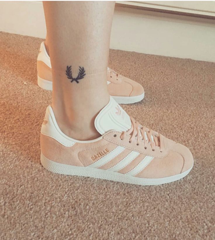 a woman's foot with a tattoo on her left ankle and pink adidas sneakers