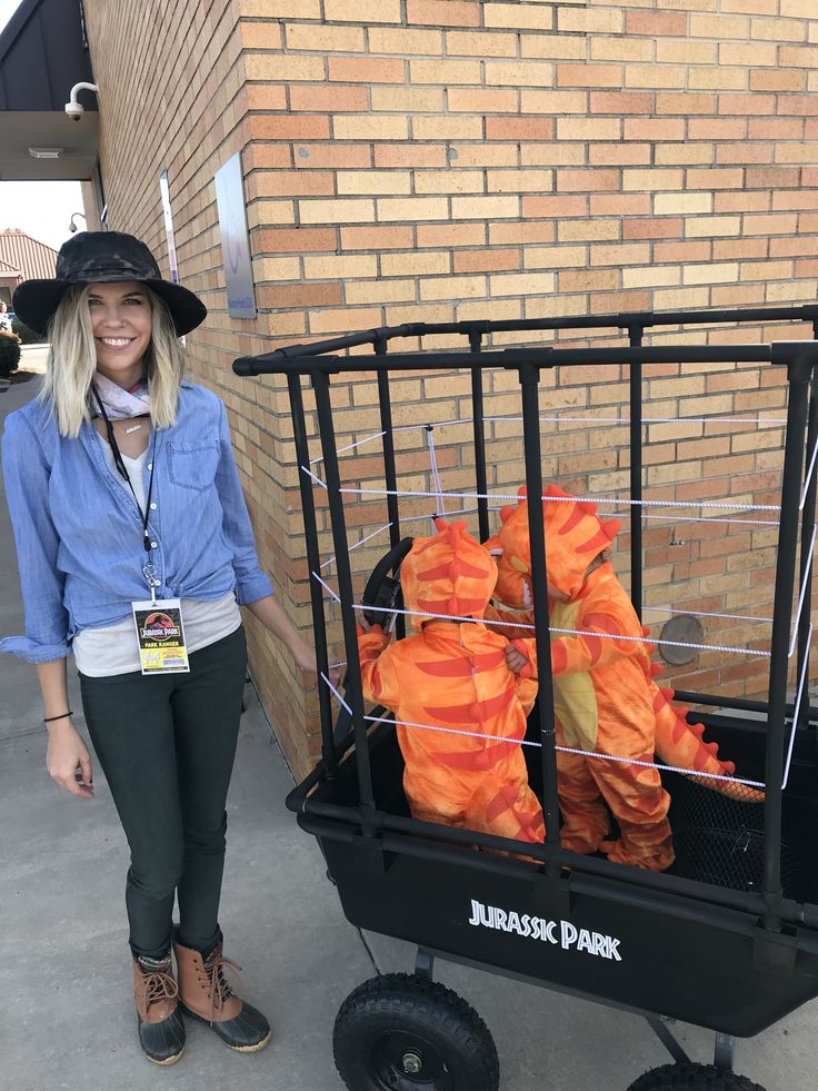 a woman standing next to a cart with stuffed animals in it's cage on wheels