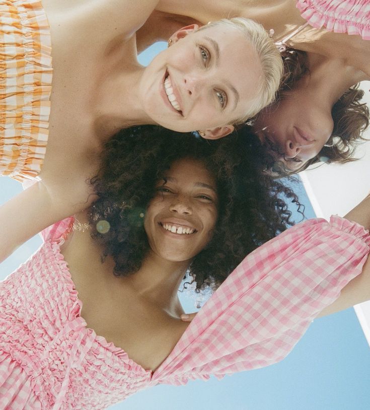 three women are standing in the middle of a circle and one is wearing a pink checkered swimsuit