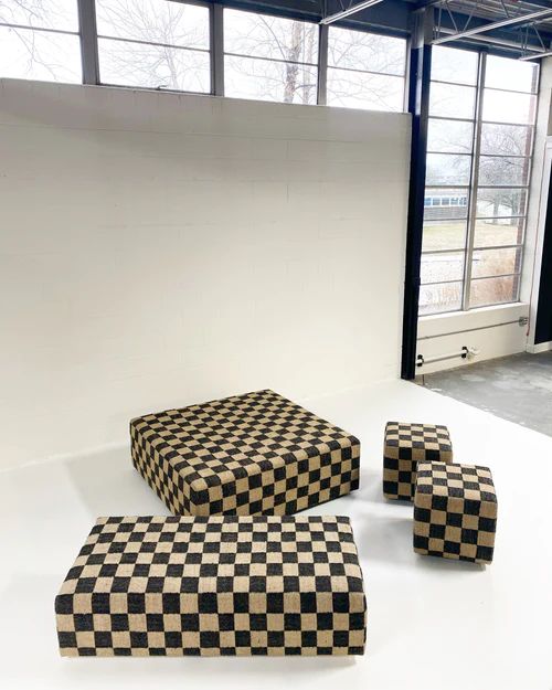 three black and white checkered ottomans sitting on top of a table in an empty room