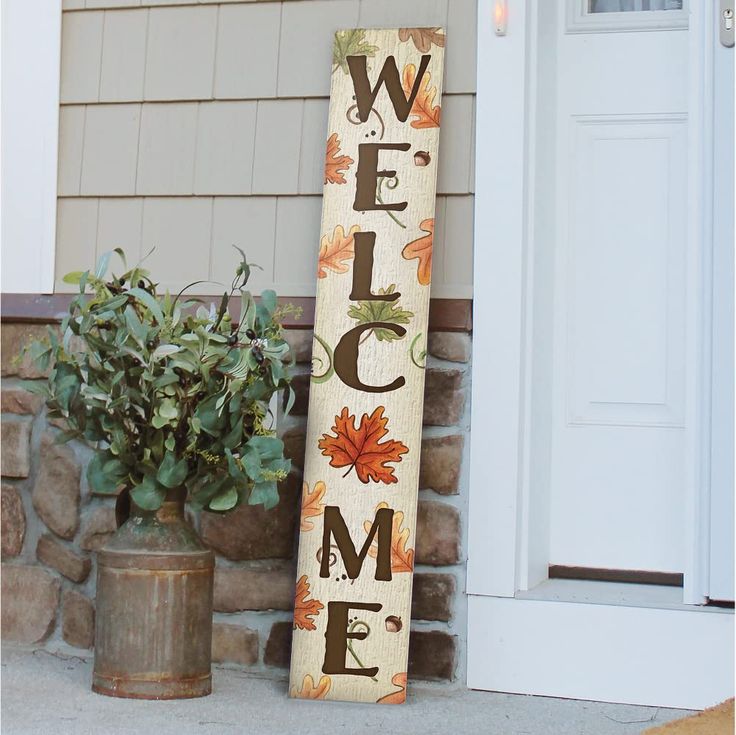 a welcome sign sitting next to a potted plant on the side of a house