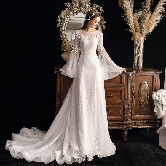 a woman is standing in front of a mirror wearing a wedding dress with long sleeves