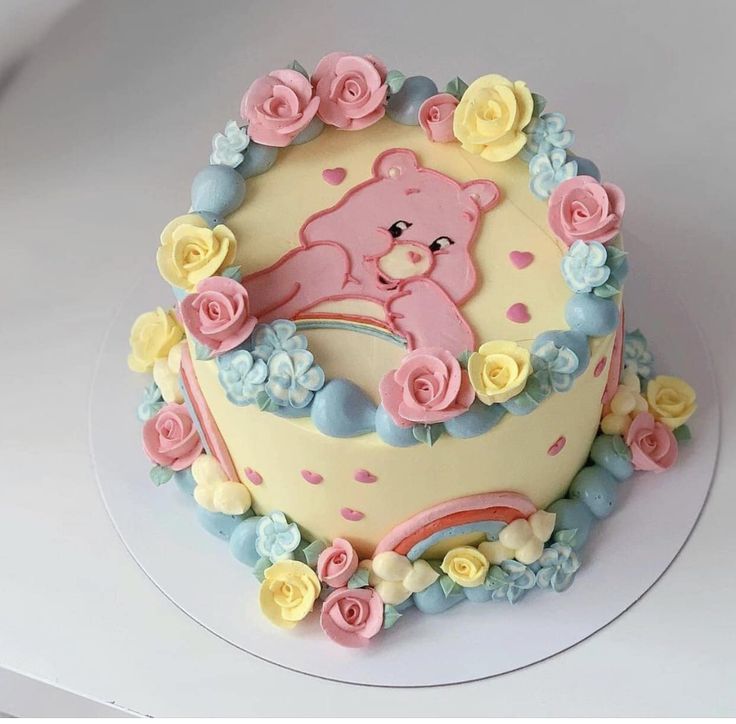 there is a cake decorated with flowers and a teddy bear on it's side