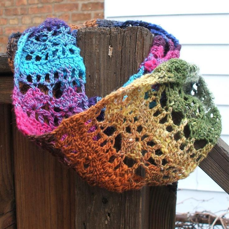 three crocheted scarves hanging on a wooden fence