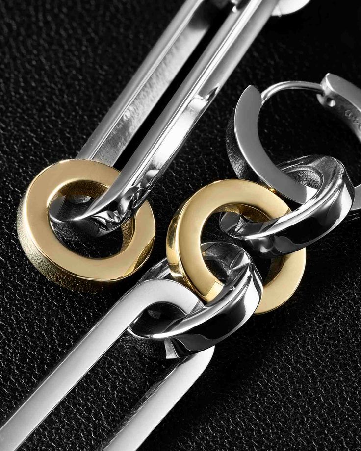 two pairs of scissors with gold and silver chains attached to them on a black surface