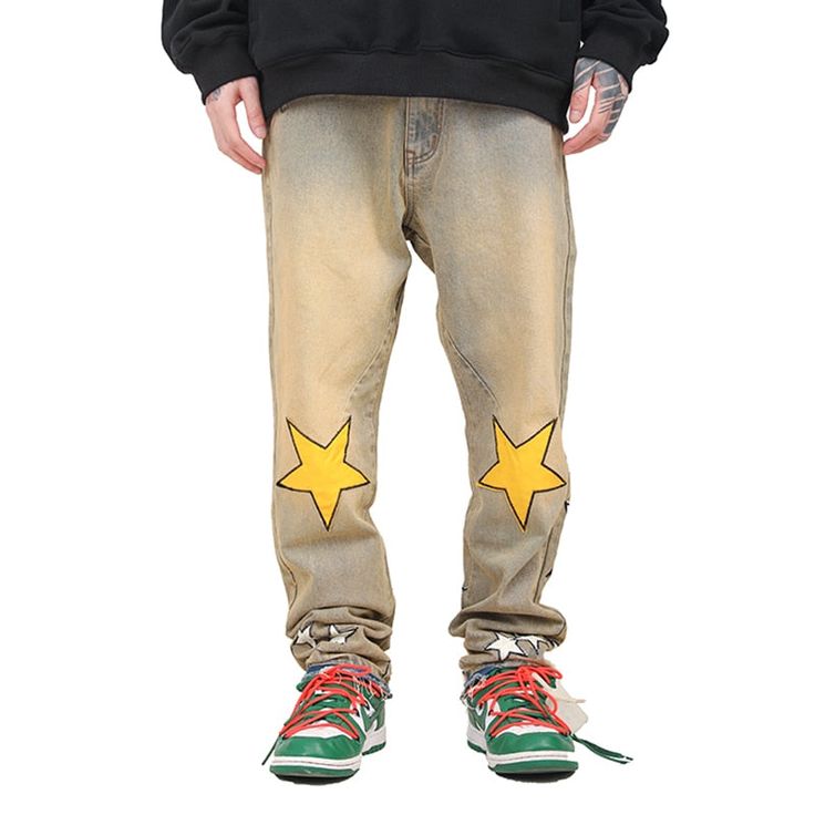 Washed-out khaki jeans with bold star appliqués. Features large yellow stars on the knees and smaller silver stars near the hem. The distressed look and frayed edges add a grunge element. Combines playful cosmic motifs with a vintage-inspired wash for a unique, statement-making style. Star Print Denim Jeans For Streetwear, Fall Star Print Denim Jeans, Trendy Cotton Jeans With Star Patch, Trendy Jeans With Star Patch For Streetwear, Casual Cotton Jeans With Star Patch, Straight Leg Star Print Bottoms For Streetwear, Casual Spring Jeans With Star Patch, Spring Casual Jeans With Star Patch, Yellow Straight Leg Jeans For Streetwear