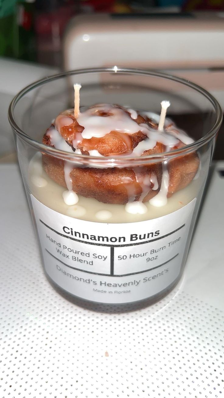 a candle that is sitting in a glass bowl on a table with cinnamon buns