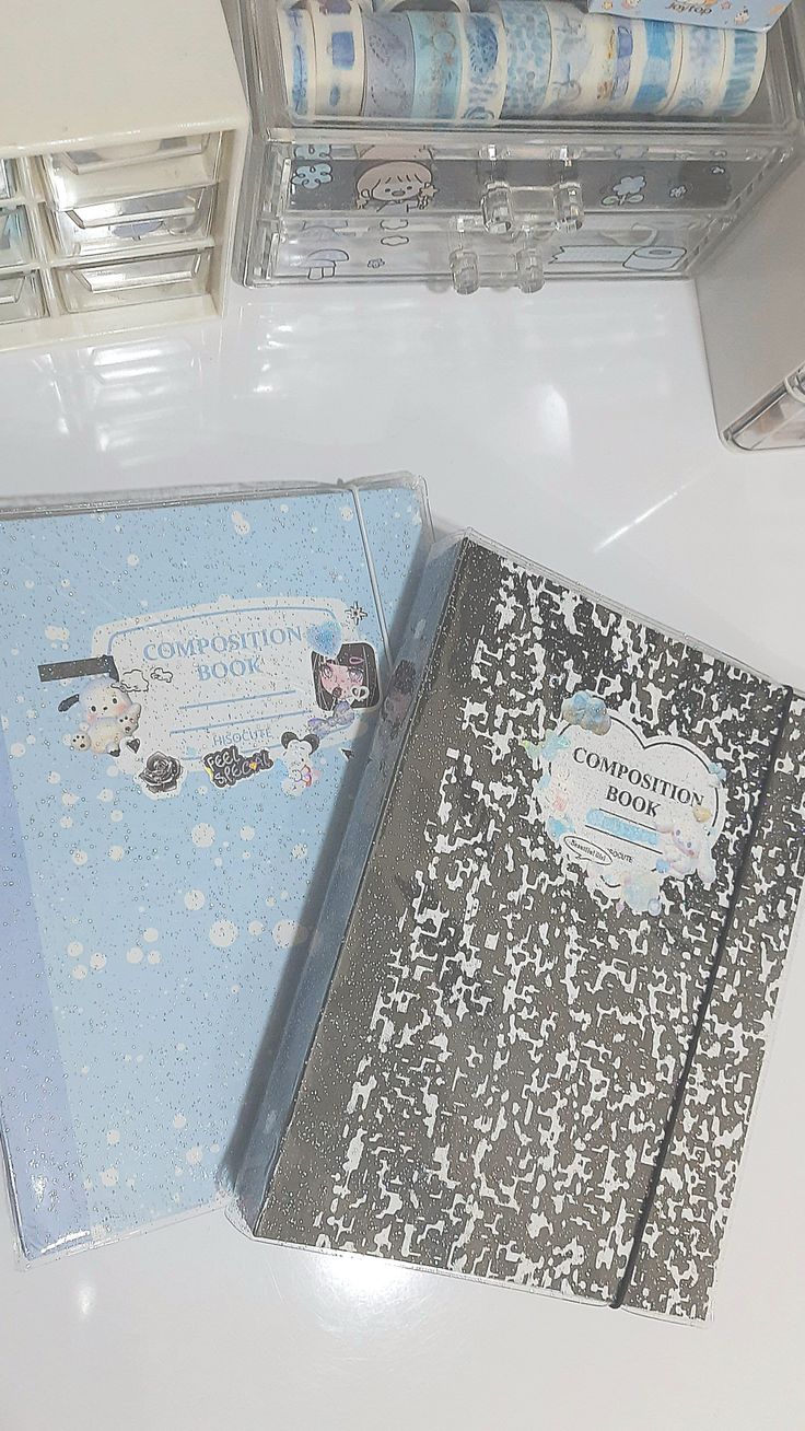 two notebooks sitting next to each other on a white table with blue and silver decorations