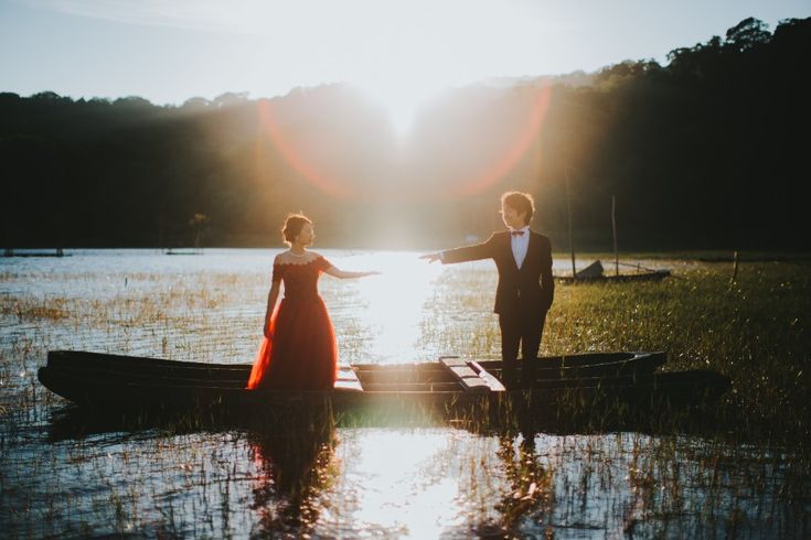 a man and woman standing on top of a boat in the water