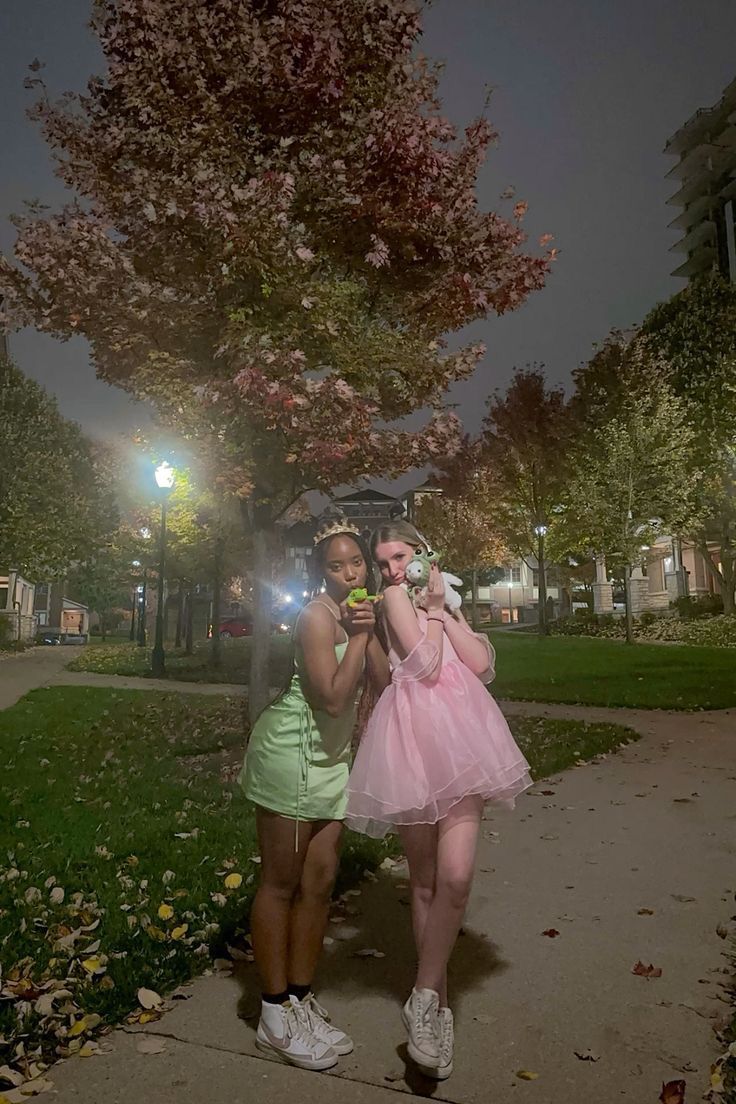 two young women standing next to each other in front of a tree with pink flowers