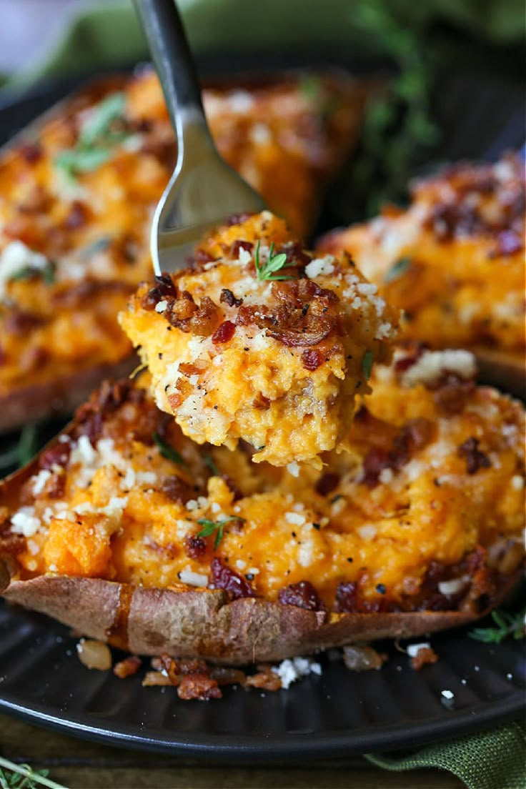 a fork is lifting some food out of a baked potato dish on a black plate