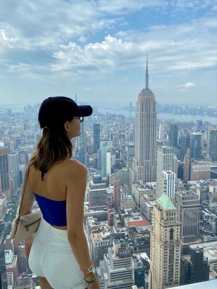 a woman standing on top of a tall building looking down at the city below her