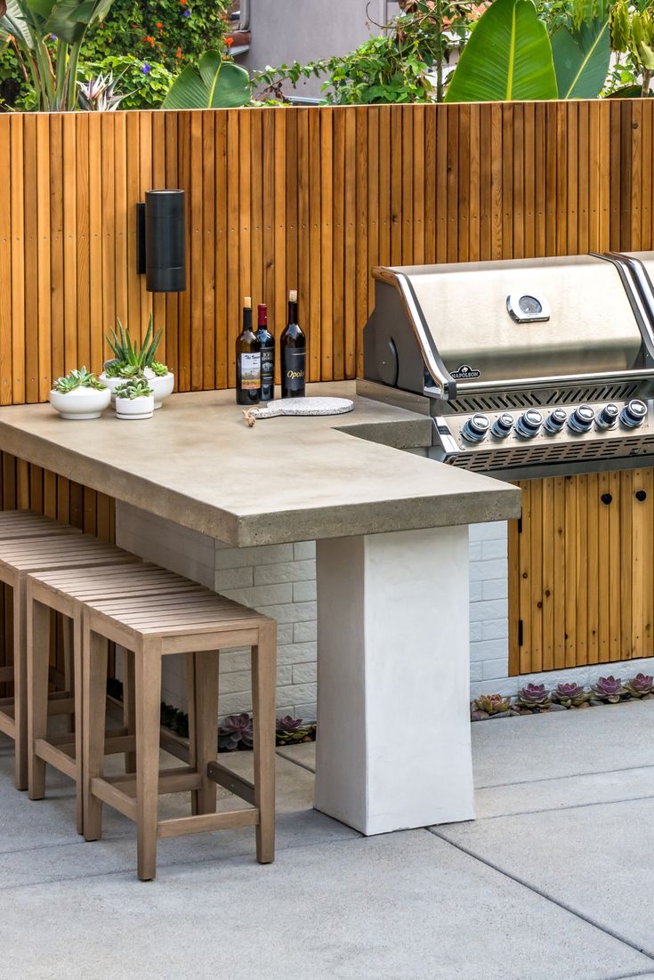 an outdoor table with two benches next to it and a grill in the back ground