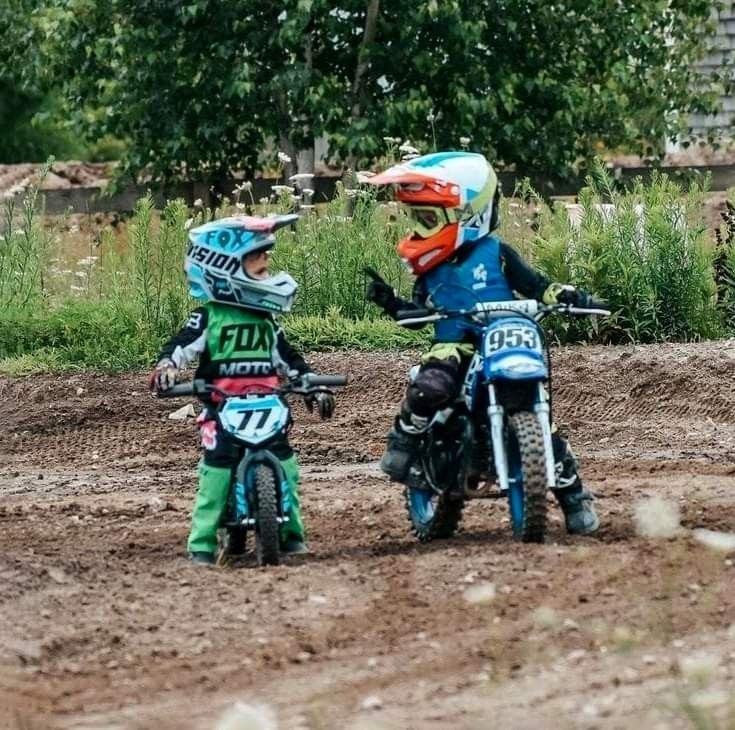 two children on dirt bikes in the mud