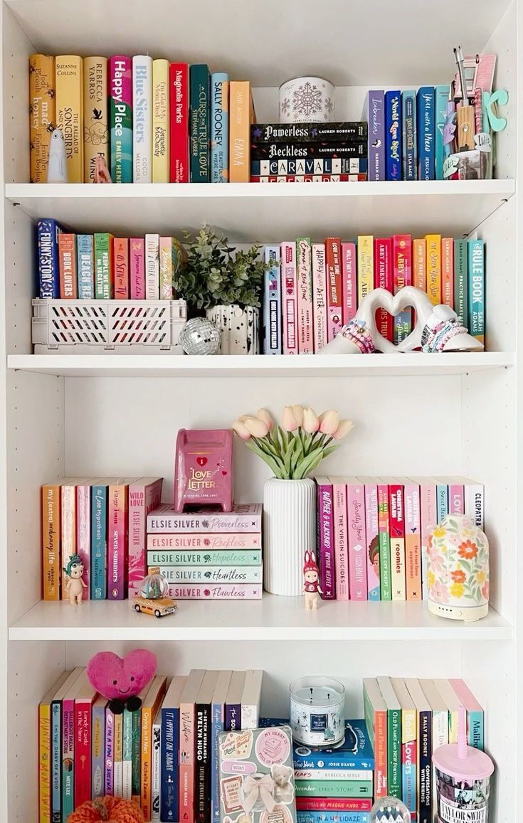 a white book shelf filled with lots of books and vases on top of it