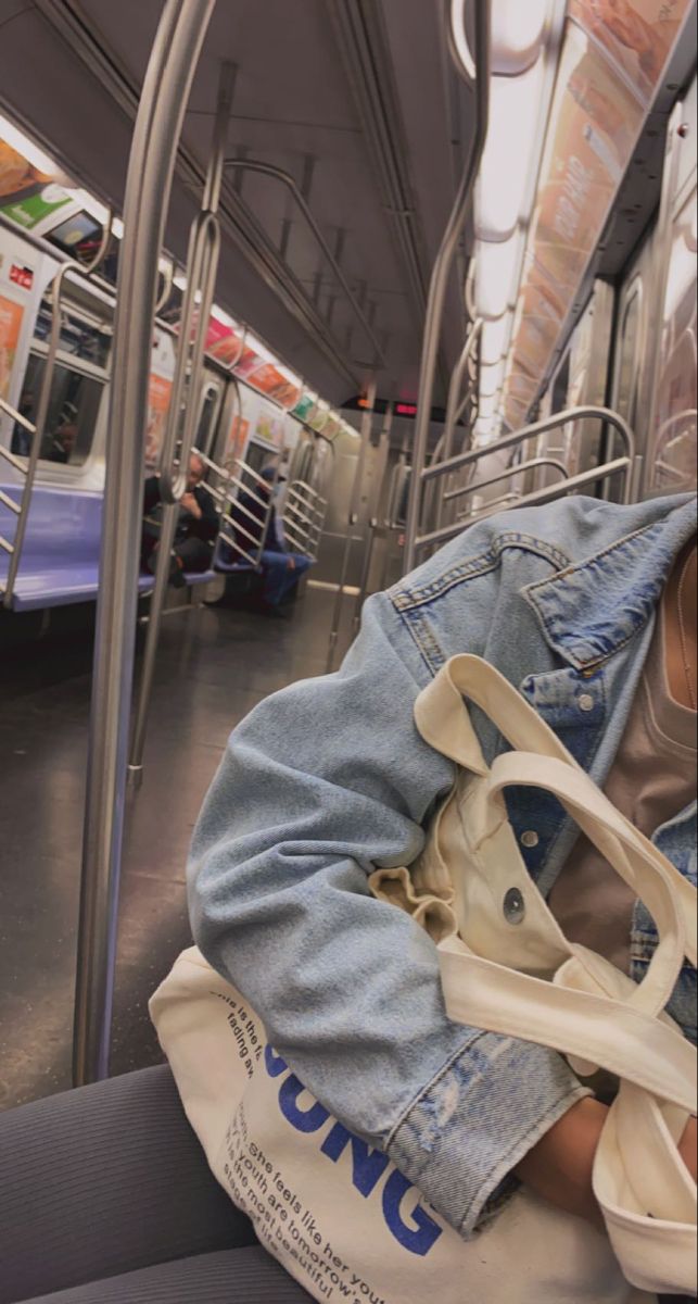 a person sitting on a subway train with their head resting on the handrails