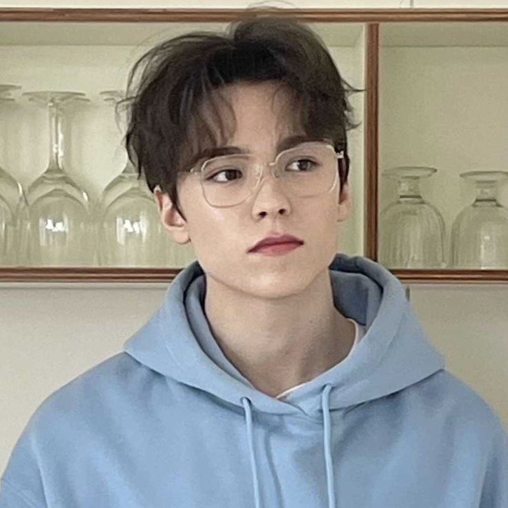 a young man wearing glasses and a blue hoodie