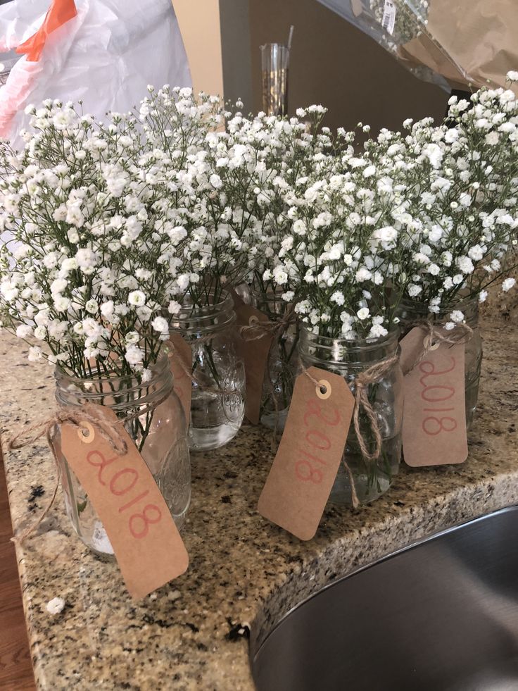 flowers in mason jars with price tags on them sitting on a granite countertop next to a sink