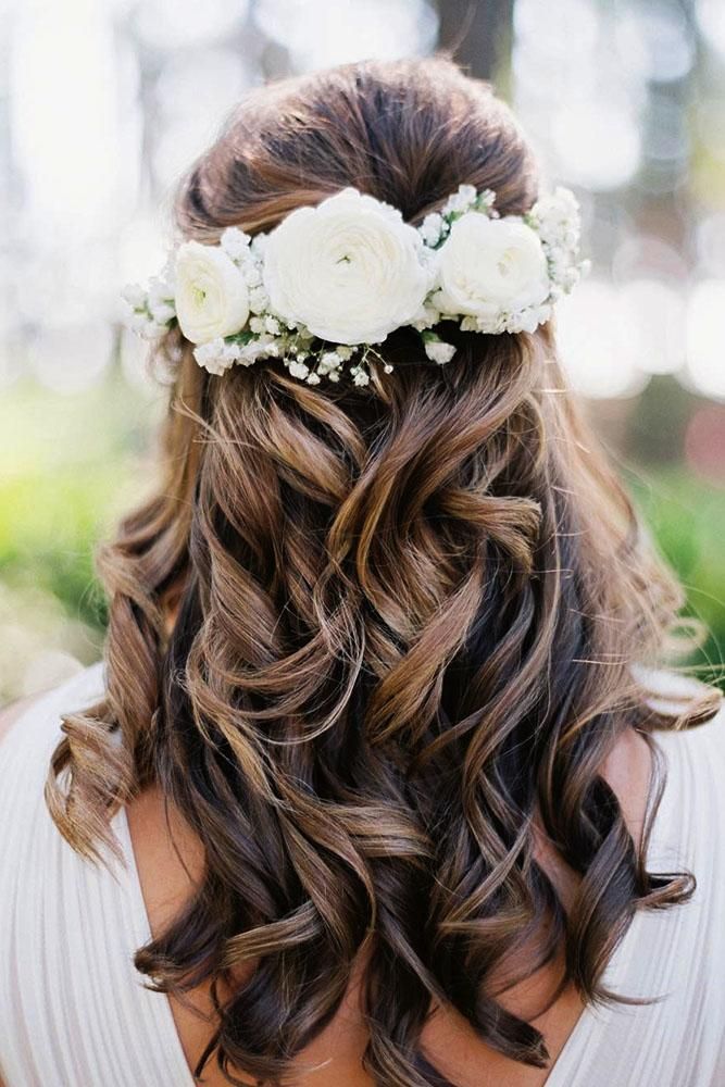 a woman with flowers in her hair wearing a white flowered headpiece on her wedding day