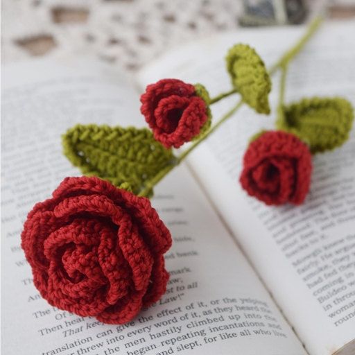 two crocheted roses sitting on top of an open book