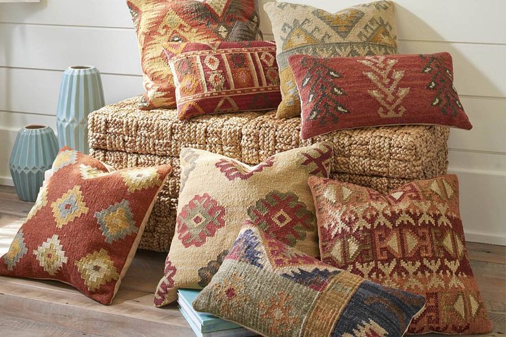 a pile of pillows sitting on top of a wooden floor next to a blue vase